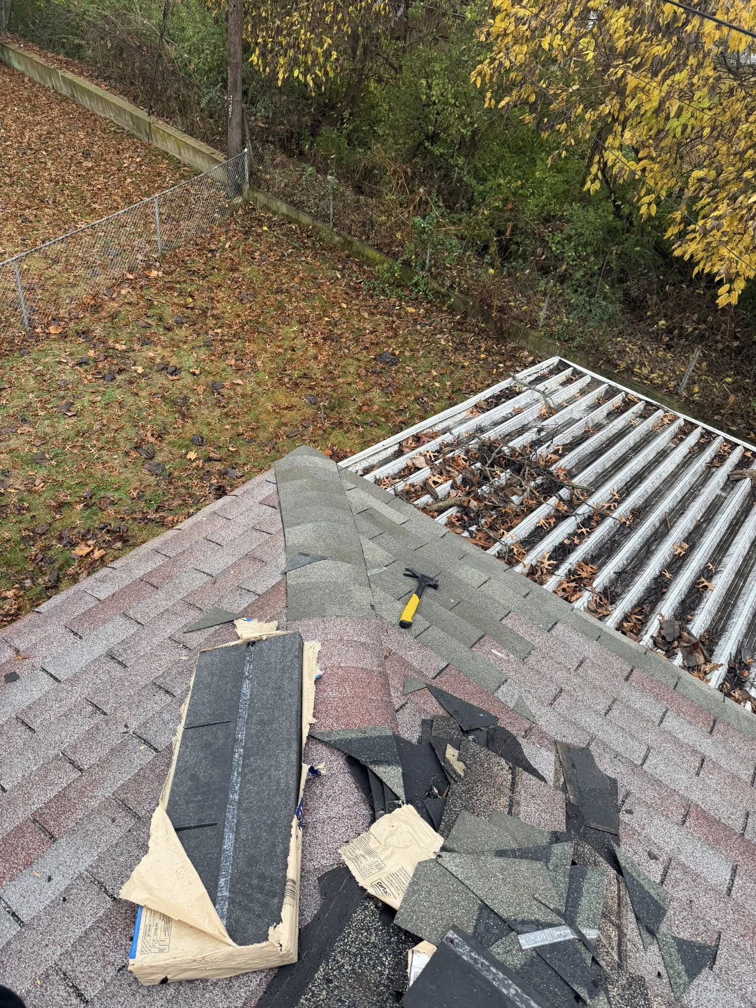 A-1 Roof Works LLC roofing crew performing mid-project roof repair with exposed shingles and gutter cleaning visible on a residential home