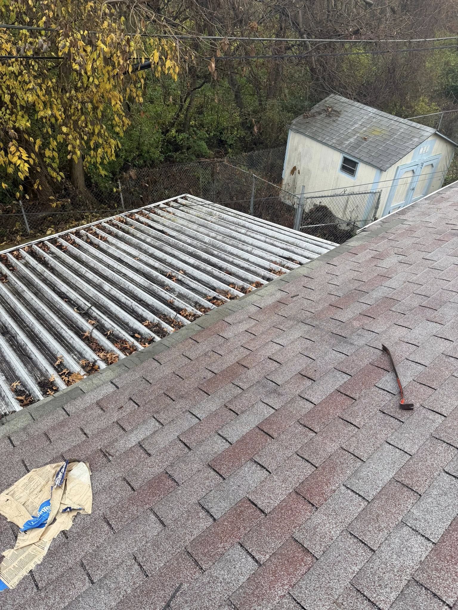 Residential roof in progress showing asphalt shingle installation with metal flashing and completed sections