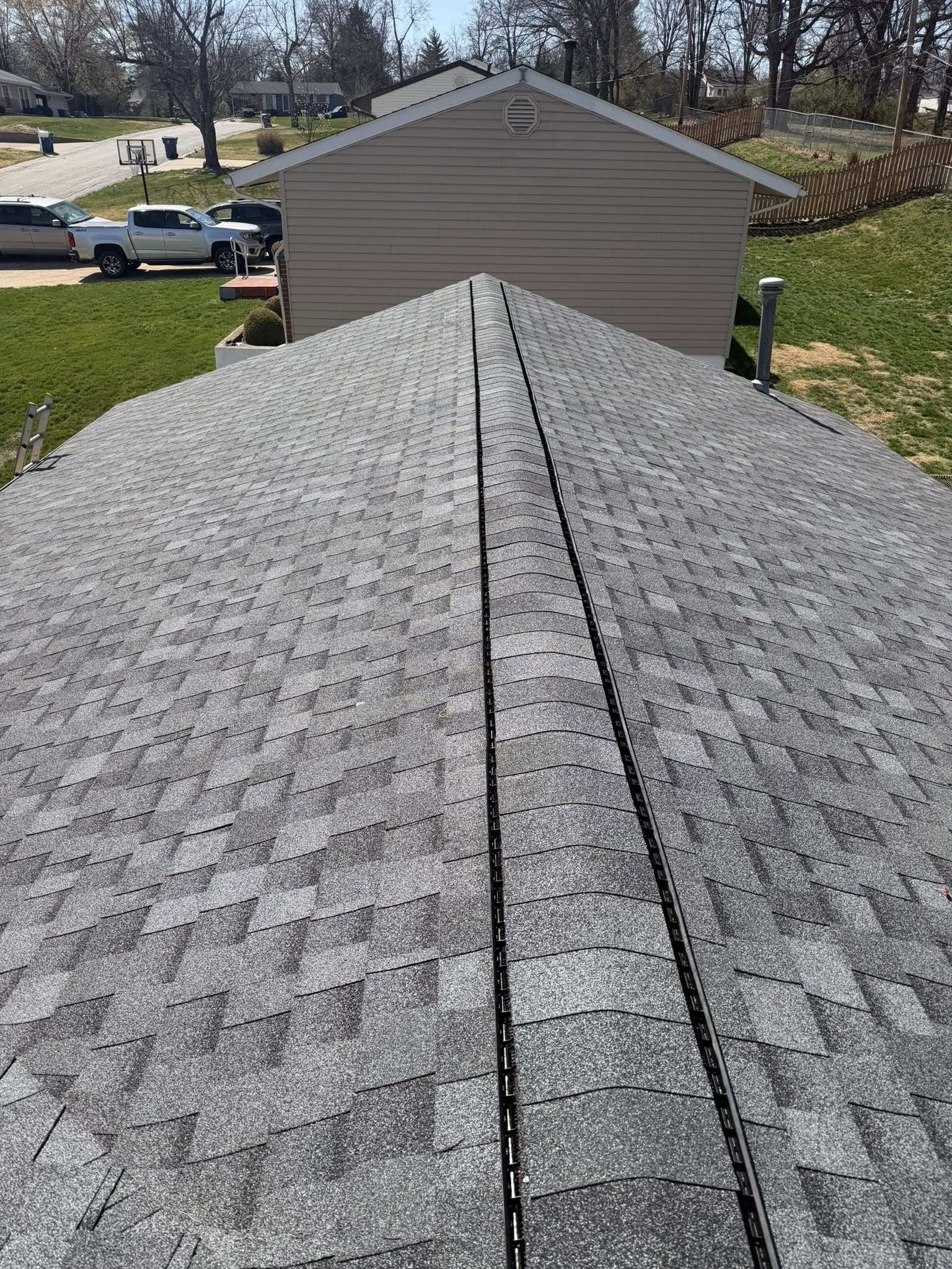 New asphalt shingle roof installation with ridge vent and gutter system on residential home