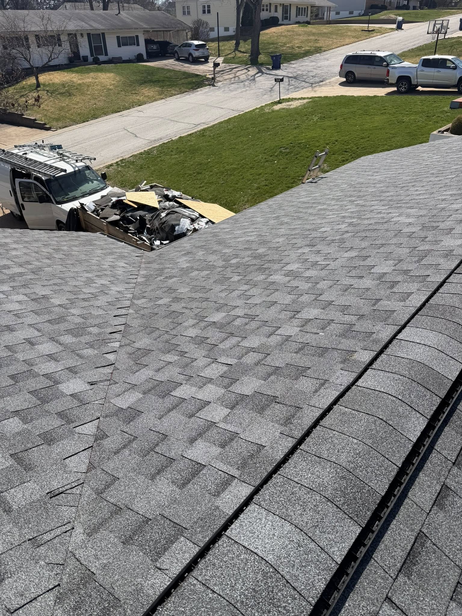 Residential roof repair in progress with shingles removed and work truck parked on driveway