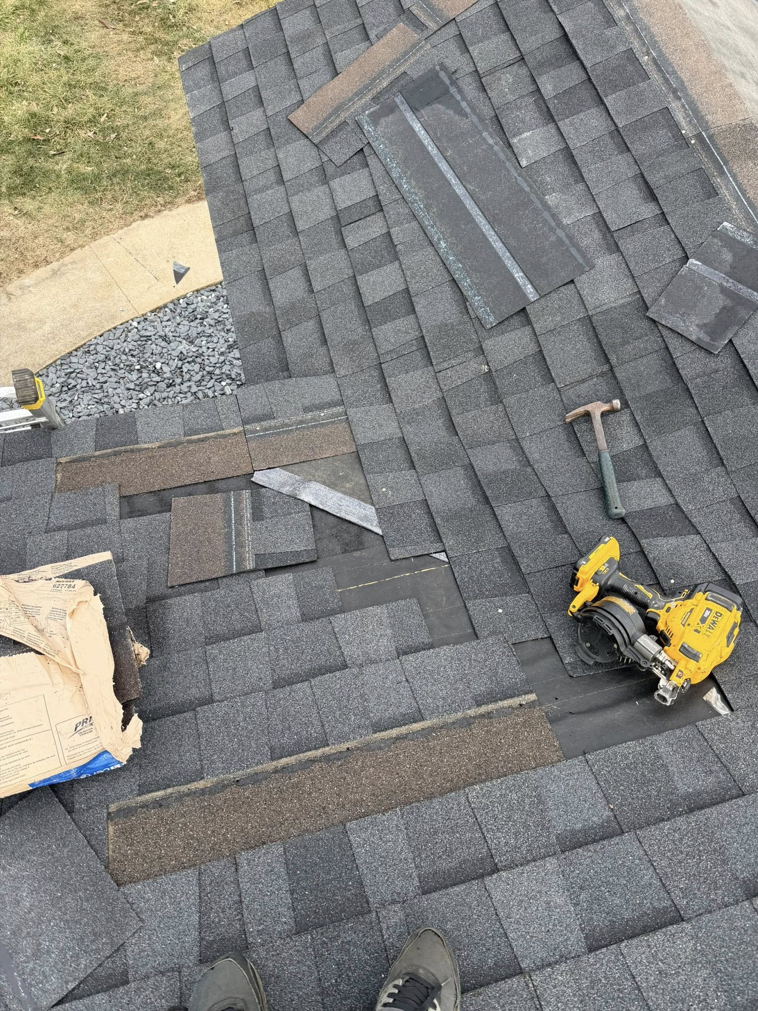 Roofer installing asphalt shingles during active roof repair work with professional tools