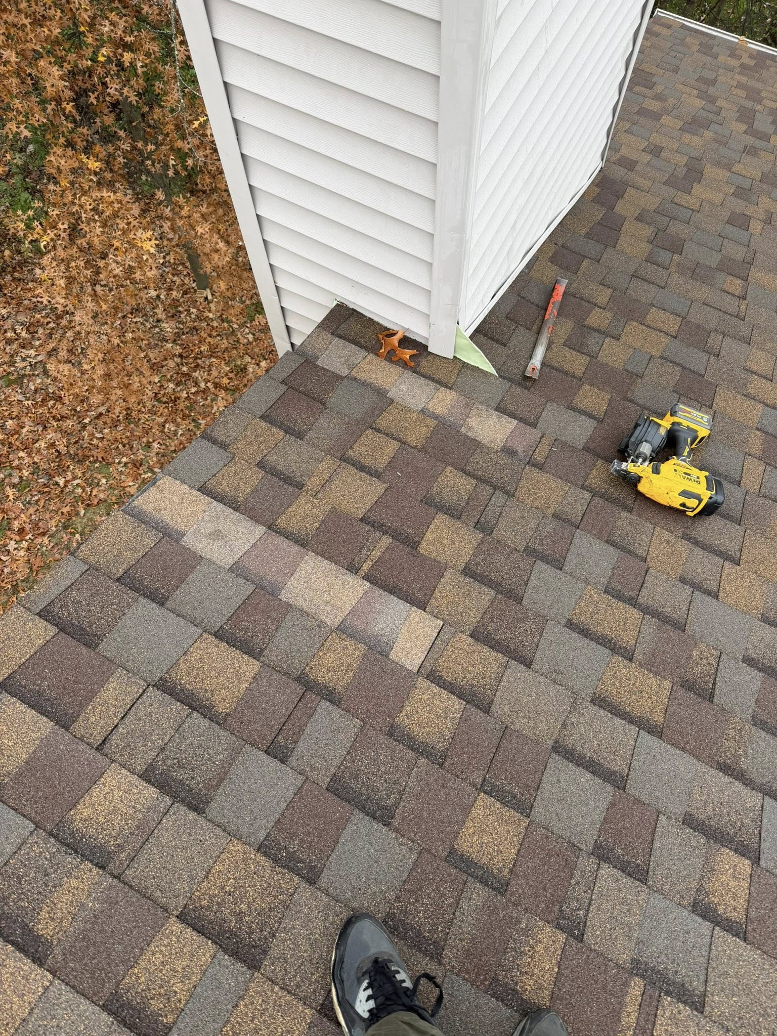 Roofer conducting on-site roof inspection with tools and equipment on residential asphalt shingle roof