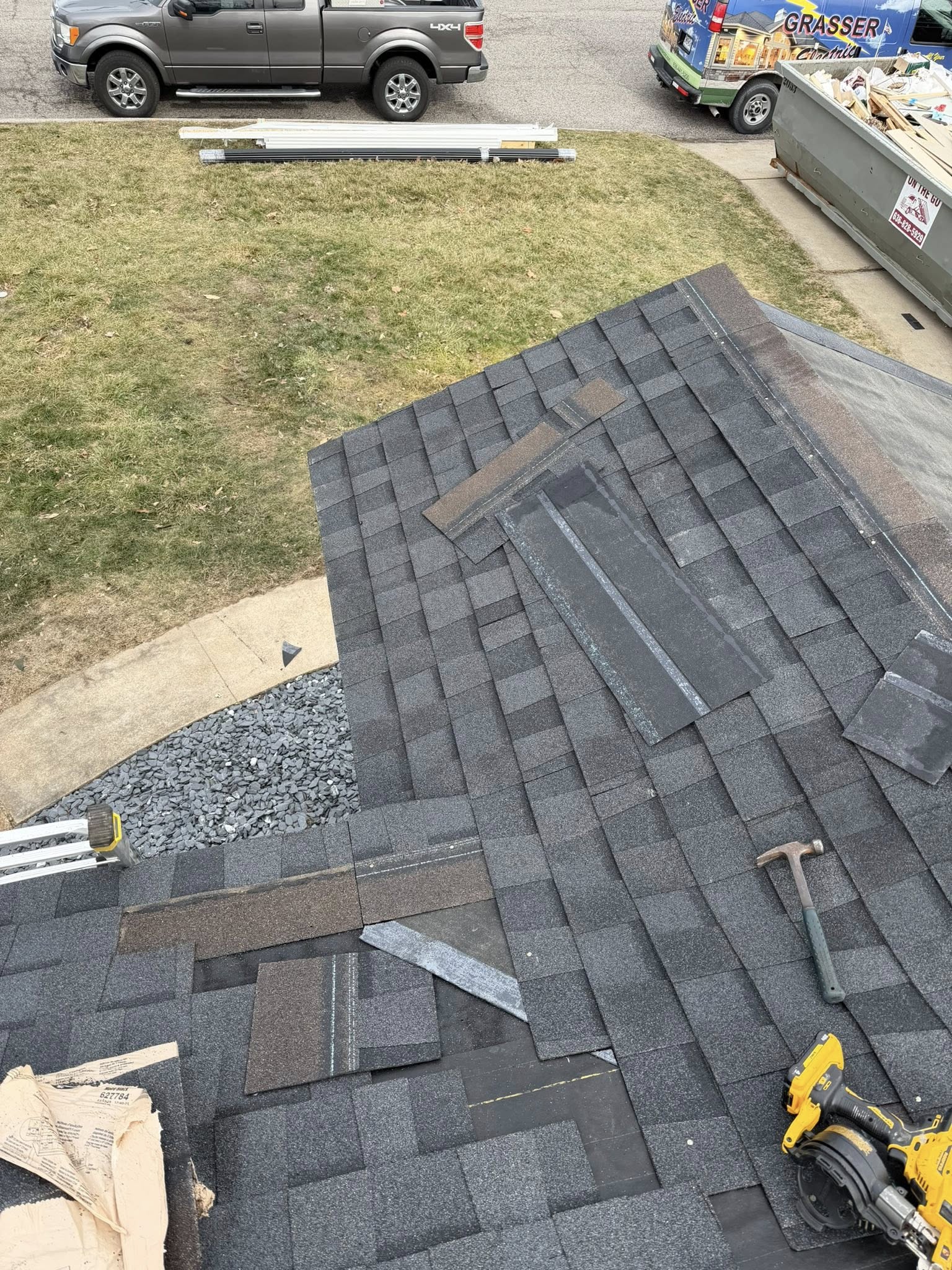 In-progress asphalt shingle roof replacement showing removed shingles and roofing tools on residential roof