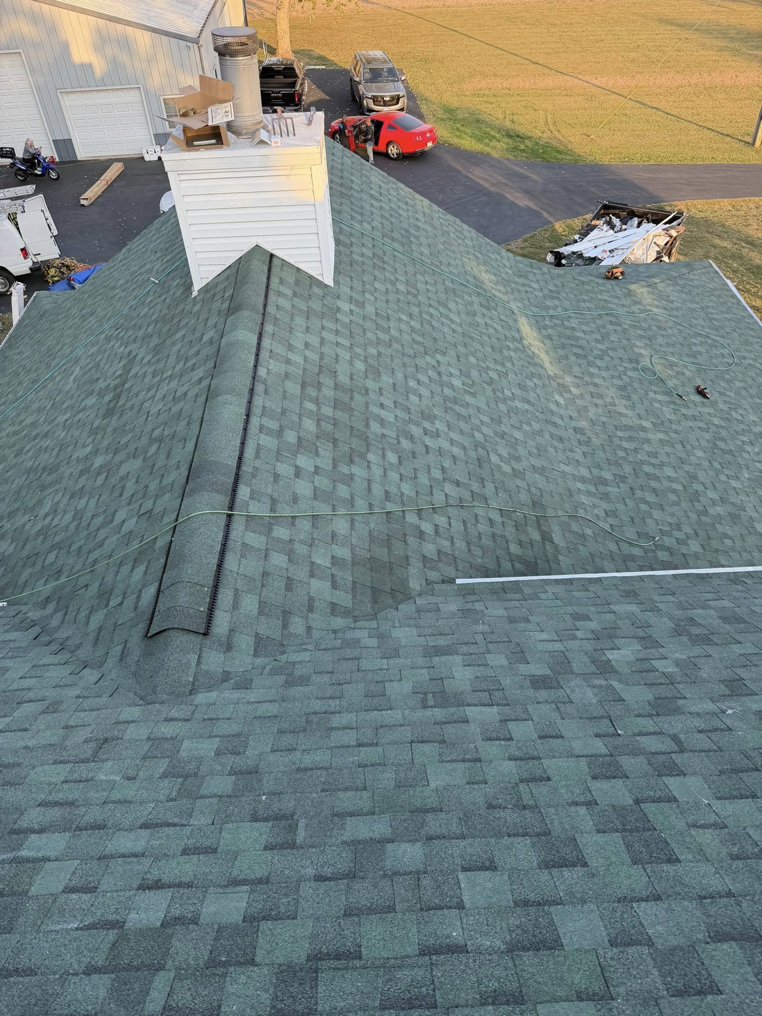 Residential roof replacement in progress showing asphalt shingles and valley flashing installation
